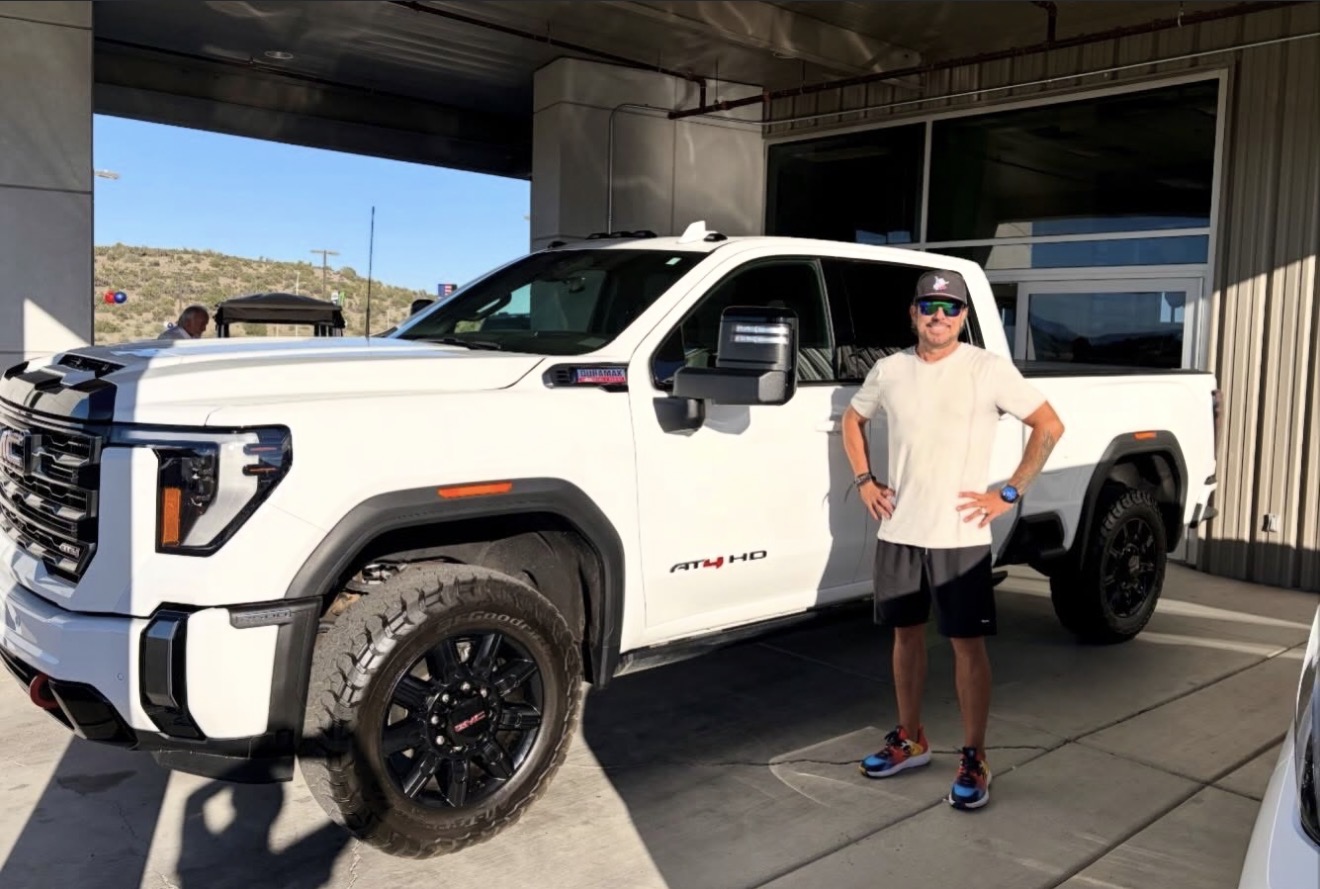 CJ's Auto Consulting client with new GMC truck at the dealership